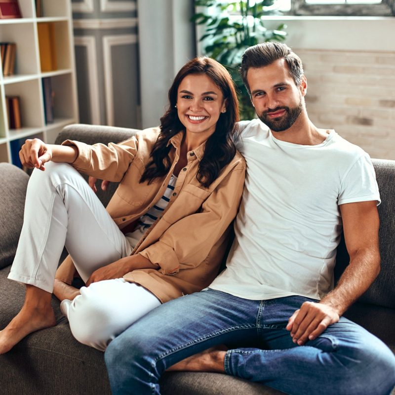 Young couple in love are sitting on the sofa at home. A married couple are relaxing in the living room.